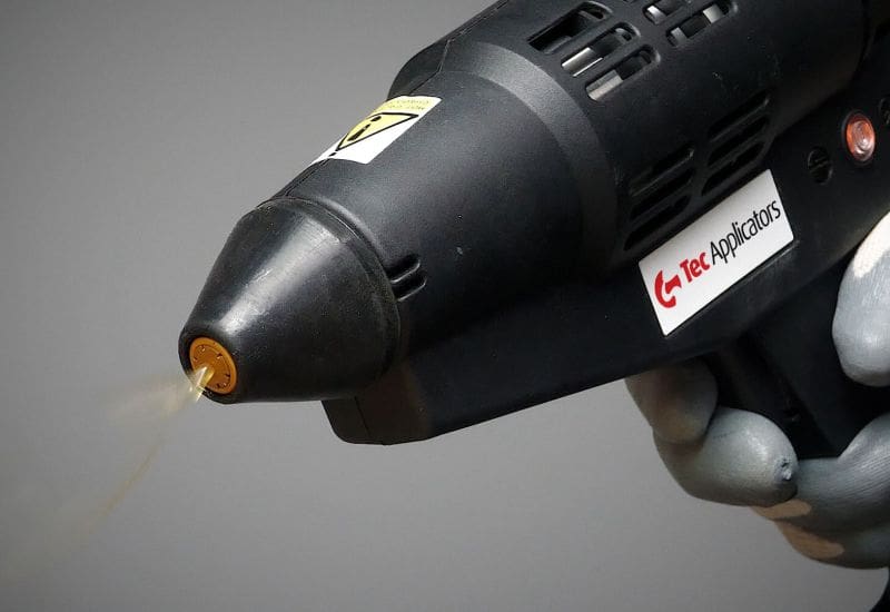 Front of Tec 7300 spray glue gun. Adhesive is being dispensed out of the front in a swirl pattern
