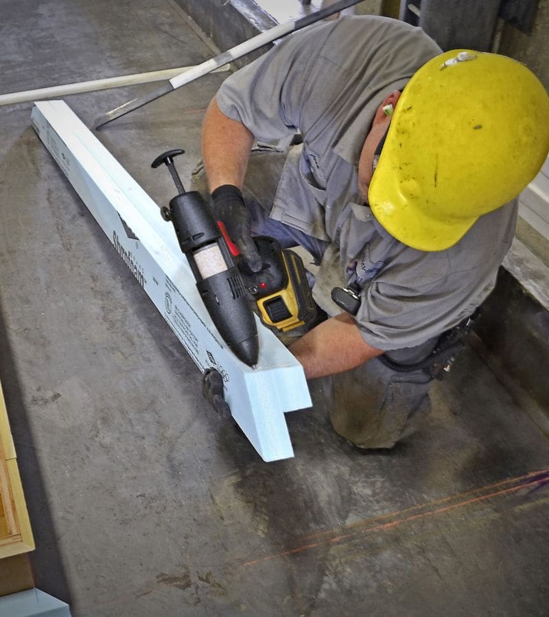 Man applying hot melt adhesive to a high density foam piece ready for bonding to a wooden precast form