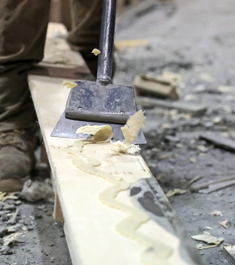 Crystalised Casttec adhesives being scrapped off a wooden panel