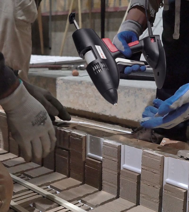 Men applying hot melt adhesive to small interior pieces on a concrete precast form