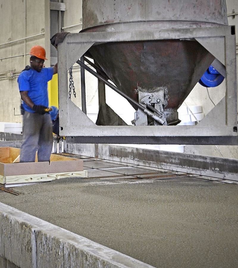 Large pouring machine dispensing concrete into a precast mould