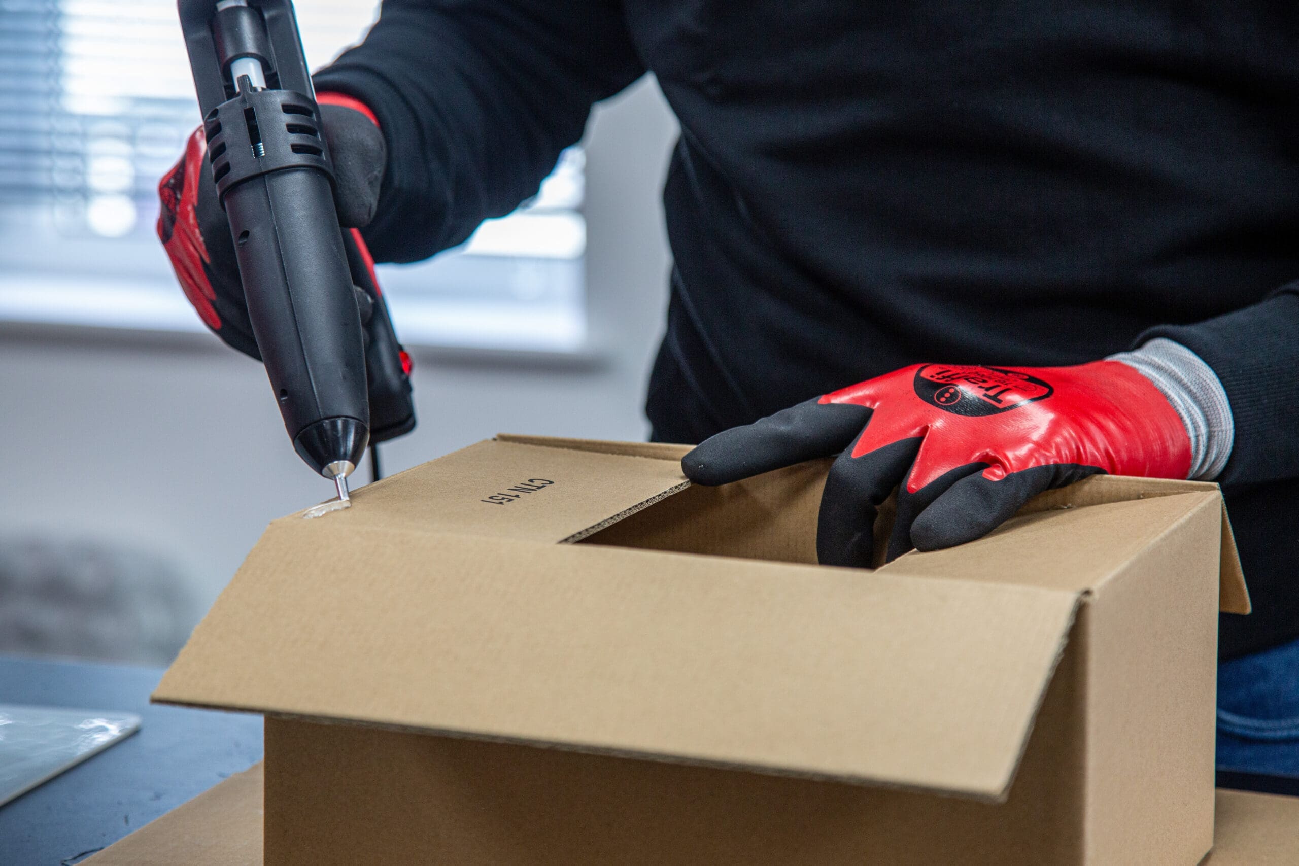 Man using hot melt glue to seal a traditional cardboard box