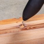 Hot melt glue gun dispensing Knottec filling compound into a large knot
