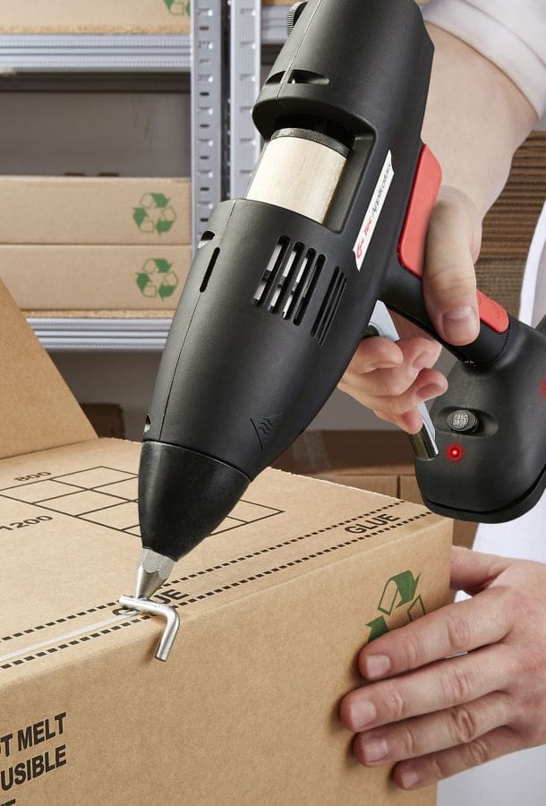 Man applying hot melt adhesive to the edge of a cardboard carton ready for sealing