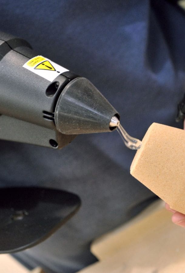 Industrial sized hot melt glue gun applying hot melt to a sand casting