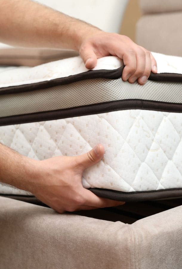 Young man choosing new orthopedic mattress in store